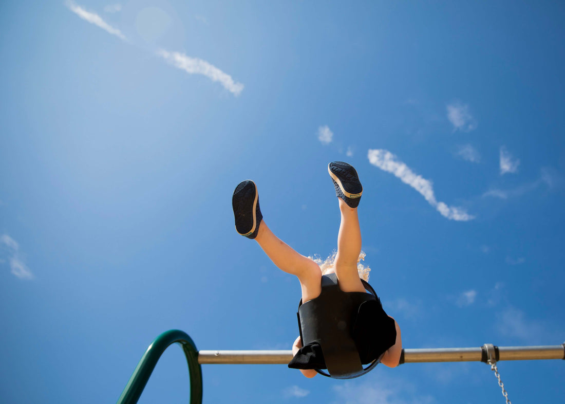 Child swinging in the sunshine under a blue sky