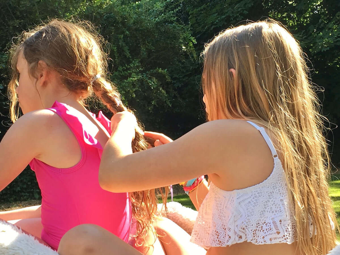 two girls in swimming costumes looking after long hair