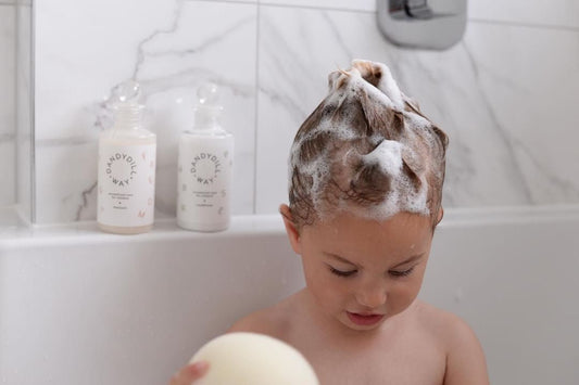 Little girl in bath tub with bubbles and shampoo