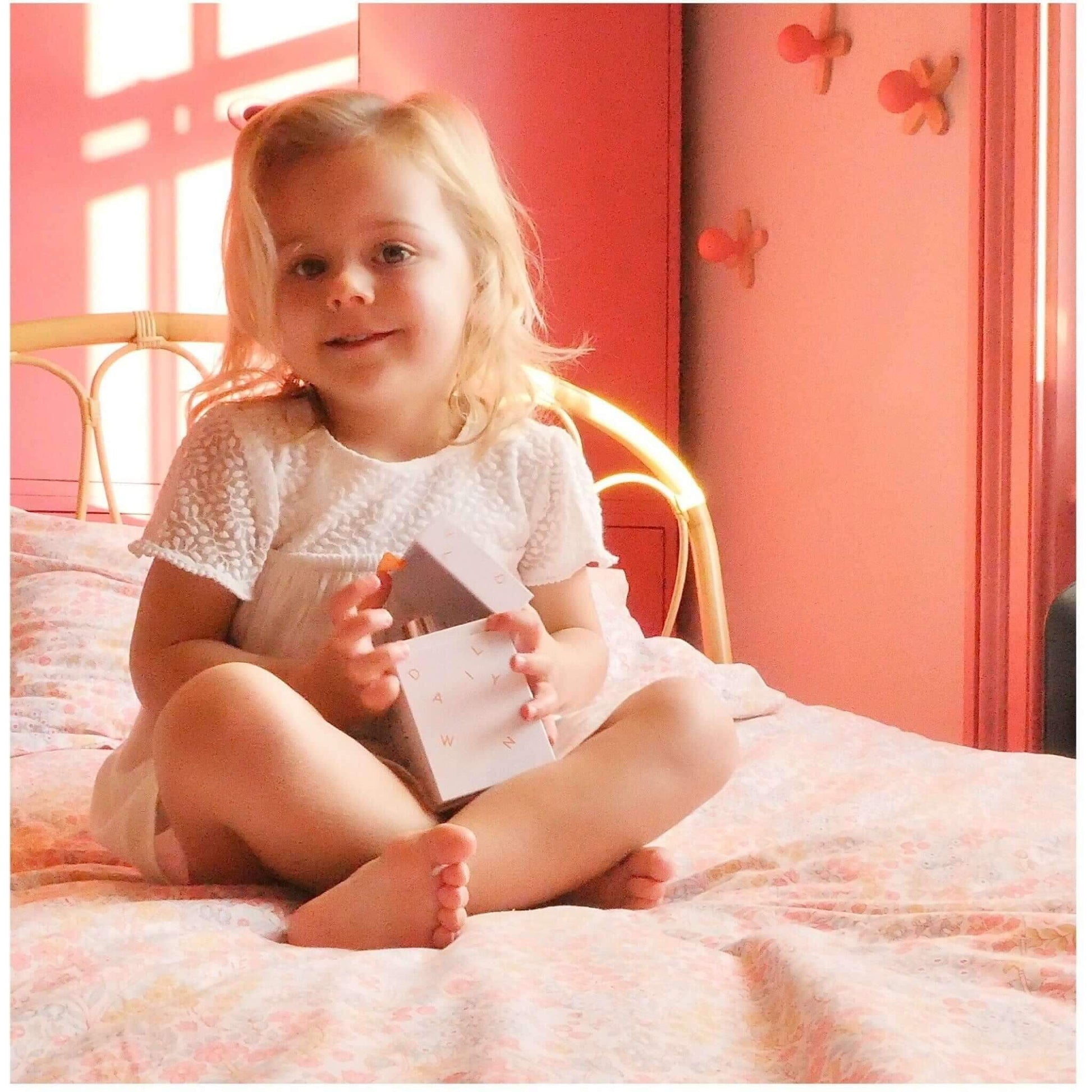 young girl laughing holding alcohol free perfume in pink bedroom