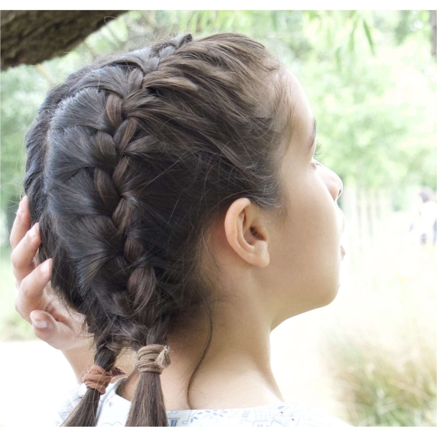 little girl with dark plaited hair outdoors